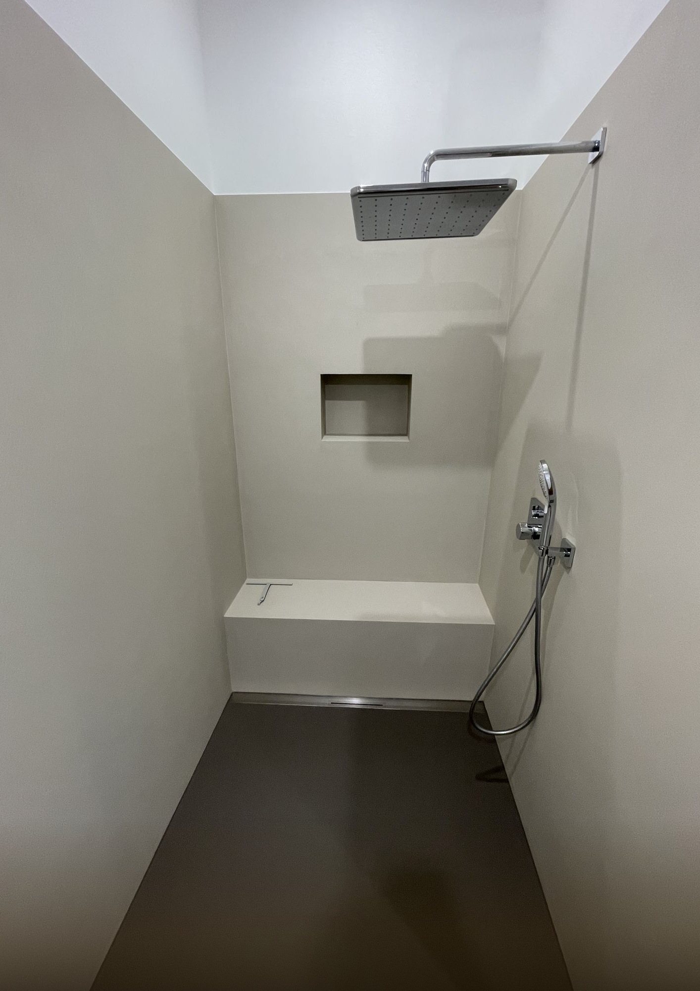 Fugenlose Dusche in warmem Sandton mit Sitzbank, Nische und Regendusche